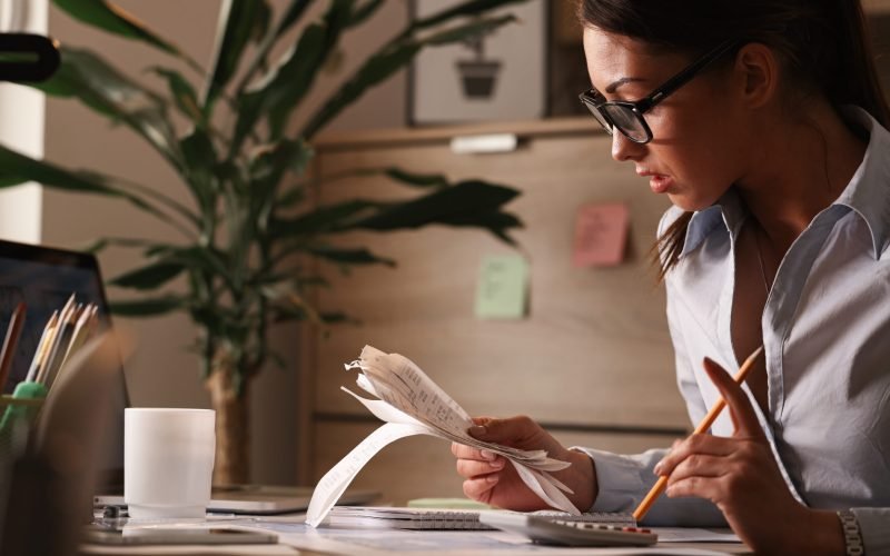 Female accountant calculating tax bills while working on finances in the office.